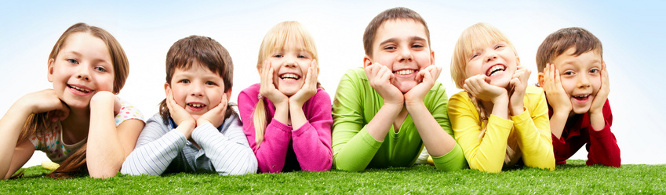 Image of happy boys and girls lying on a green grass